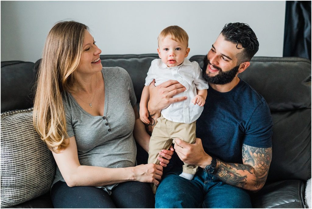 Family of three with a one year old boy. lifestyle First birthday pictures on the couch at home. by Renee Ash New Jersey photographers