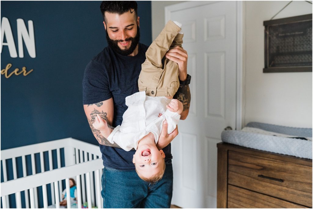 Dad playing with his one year old son in the navy blue, white, and gold nursery. lifestyle First birthday pictures at home. by Renee Ash New Jersey photographers
