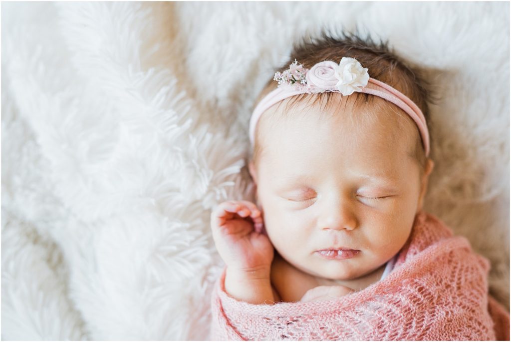 Sleeping newborn baby girl wrapped in pink on a white fur blanket. Renee Ash Photography NJ Newborn photographers
