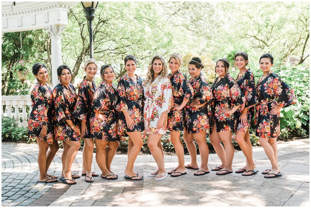 Bride with her bridesmaids in their matching floral robes as she gets ready on her wedding day at the Brownstone.  Renee Ash Photography