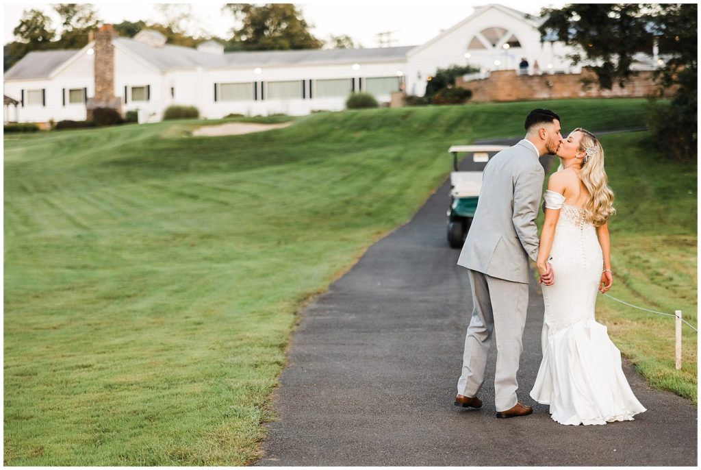 Bride and Groom kissing at sunset with their nj weddiing venue in the background. Renee Ash Photography