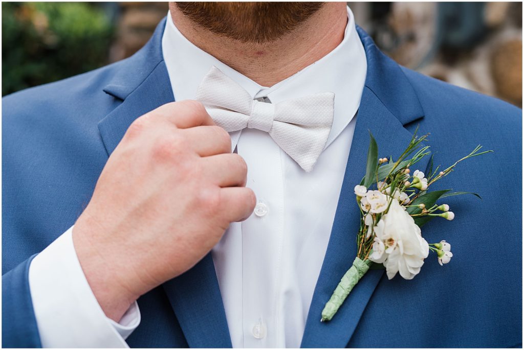 Groom in Navy blue suit and white bow tie, and a green and white boutonnière during a Spring wedding at The Olde Mill Inn Wedding Venue in Northern NJ. by Renee Ash Photography 
