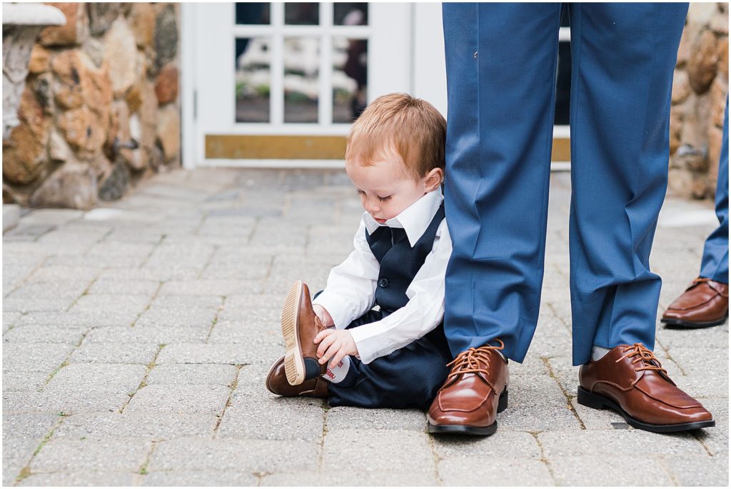 toddler Ring bearer, putting on his shoes on the wedding day of his mom and dad at the Olde Mill Inn Wedding Venue in Northern NJ. by Renee Ash Photography 