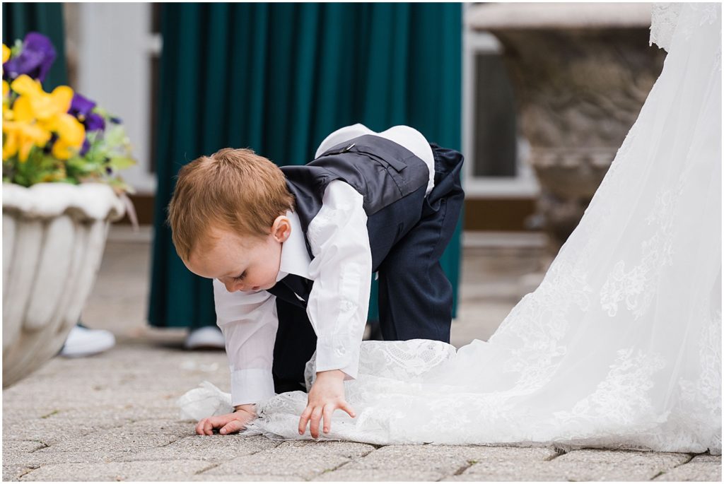 Bride and Groom's son playing with the bride's dress during their courtyard ceremony at The Olde Mill Inn Wedding Venue in Northern NJ. by Renee Ash Photography 