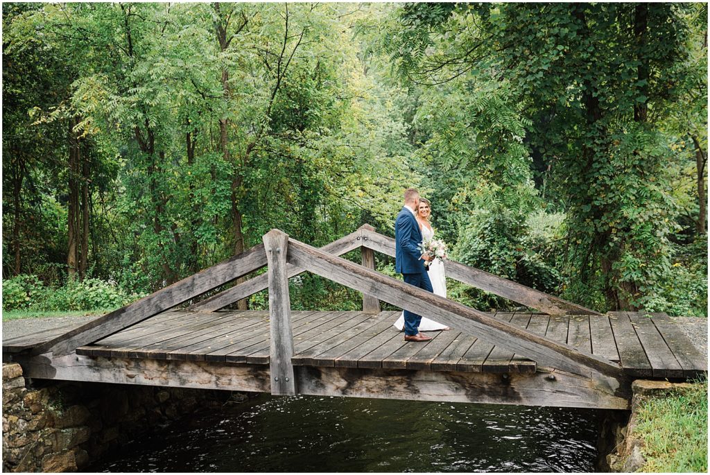 bride and groom on a bridge over a waterfall Waterloo Village Wedding Venue  New Jersey Renee Ash Photography