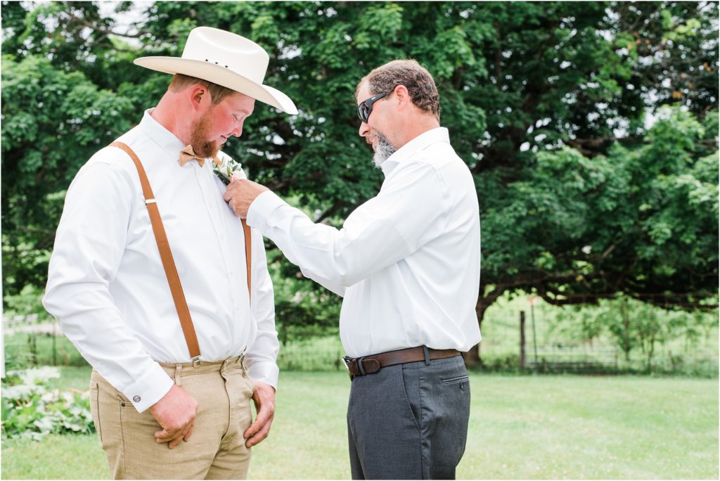 father of the groom putting on his son's boutonniere on his wedding day. 