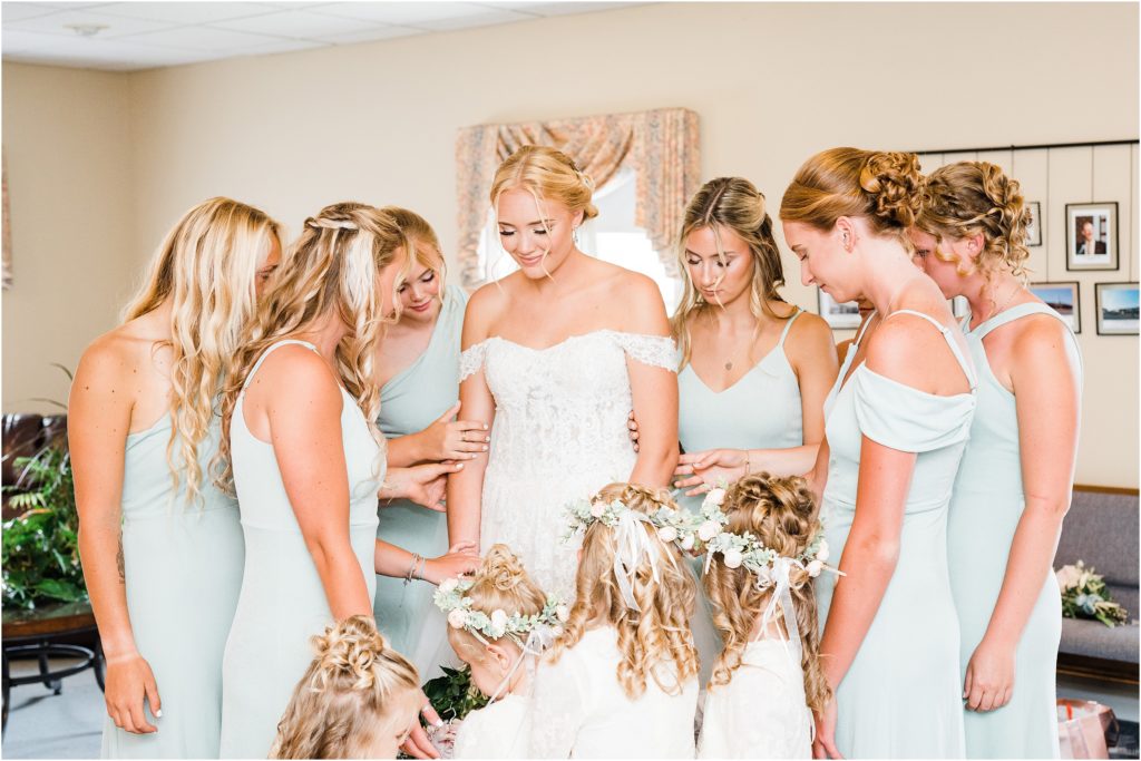 bridesmaids and flower girls praying over the bride before she walks down the aisle. 