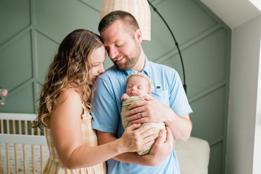 new parents holding their newborn daughter in the nursery during an in home newborn photoshoot. New Jersey newborn photographers Renee Ash Photography