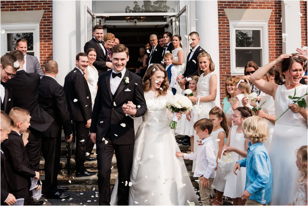 Grand exit from the church with a white flower petal toss. Reformed baptist church of Lafayette wedding. Traditional black and white wedding by Renee ash photography