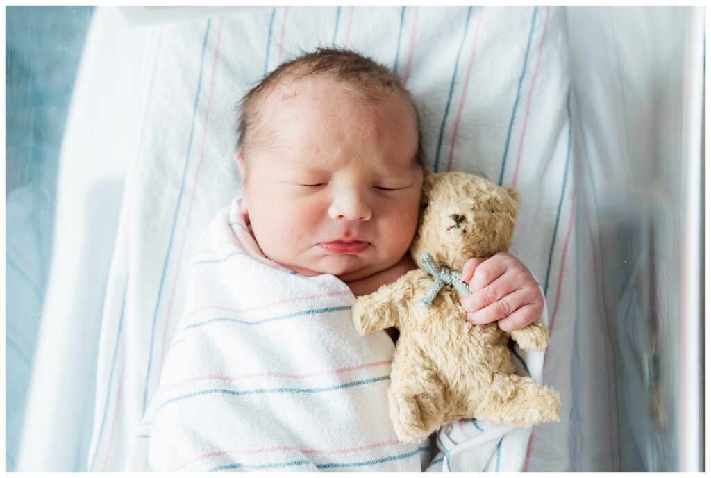 Baby holding a teddy bear during his first photo shoot at Morristown Hospital Newborn Photography NJ newborn photographer. Renee Ash Photography