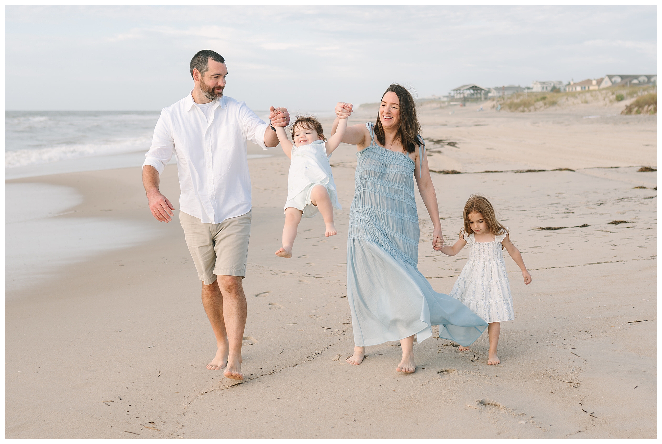 Long Beach Island New Jersey Shore family photographer. Family in blue and white beach photo shoot outfits playing in the sand and enjoying natural candid photos together on LBI, Beach Haven