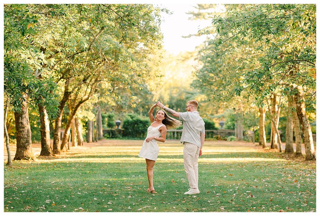 Romantic North NJ engagement photography session at Skylands Manor featuring a joyful couple walking through botanical gardens in soft golden hour light.