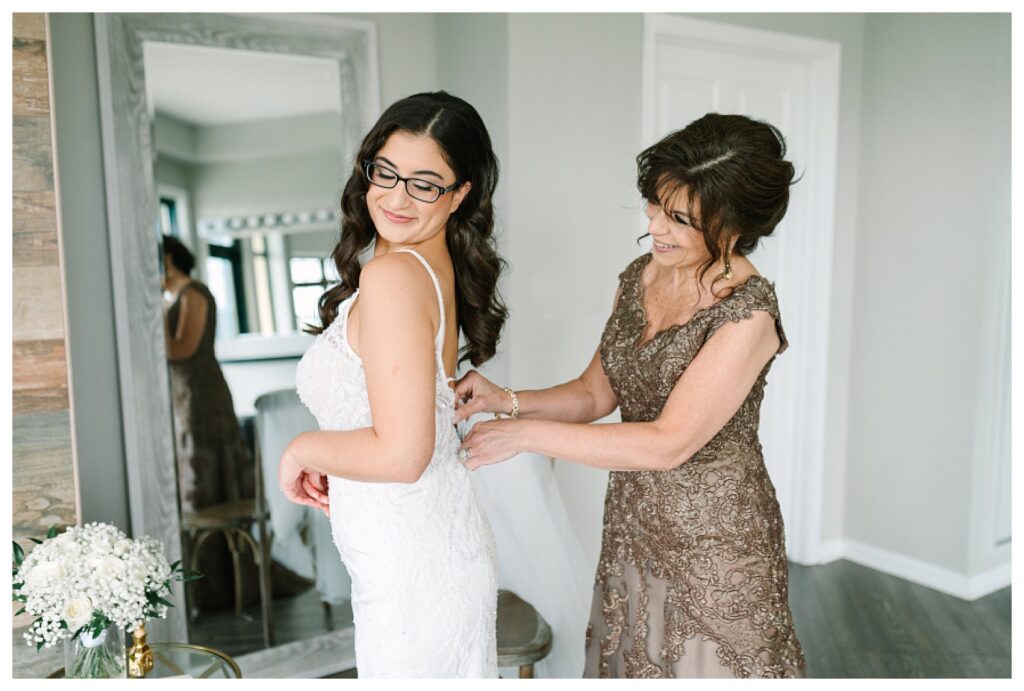 Bride with her mother buttoning up the back of her dress during her Wedding at Mountain Creek Resort Venue Photographer renee Ash Photography