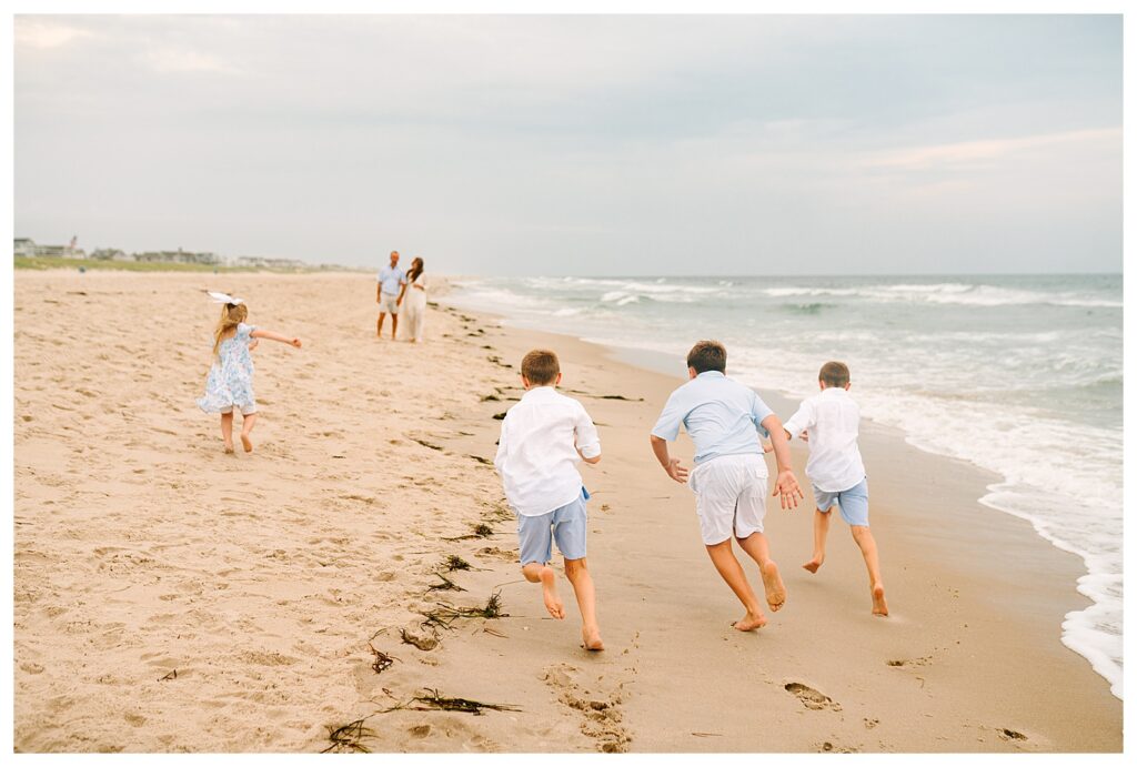 Candid photo of children running toward the ocean waves during a Beach Haven family photography session