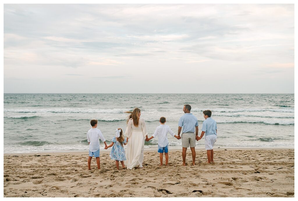 Mom and dad walking hand in hand with their children on a sandy LBI beach at sunset